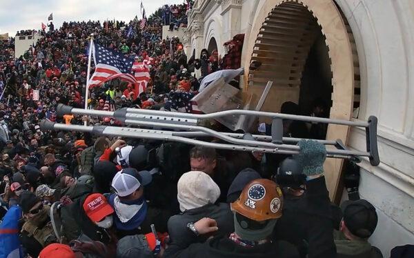 A protester hands off two stolen crutches outside the Lower West Terrace tunnel at the U.S. Capitol on Jan. 6, 2021. (Special to The Epoch Times)