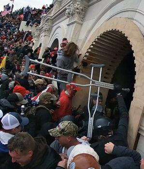 A rioter uses two stolen crutches to assault police inside the Lower West Terrace tunnel on January 6, 2021. (Special to The Epoch Times)