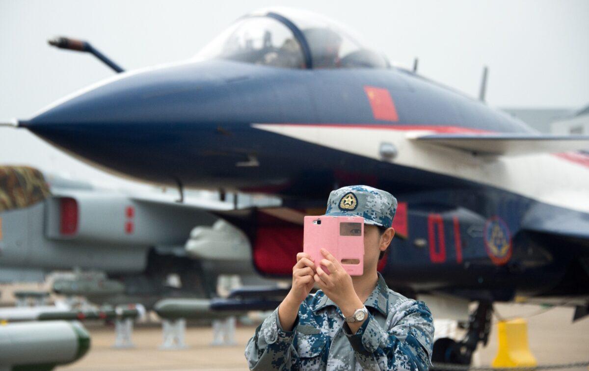 A soldier of the People's Liberation Army Air Force (PLAAF) takes a selfie in front of a J-10 jet fighter ahead of the Airshow China 2014 in Zhuhai, Guangdong Province, on November 10, 2014. (Johannes Eisele/AFP via Getty Images)