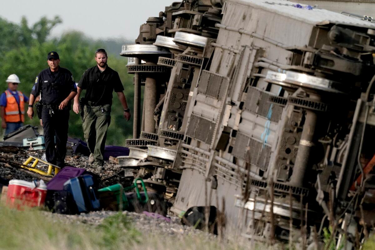 Law enforcement personnel inspect the scene of an Amtrak train which derailed after striking a dump truck near Mendon, Mo., on June 27, 2022. (Charlie Riedel/AP Photo)