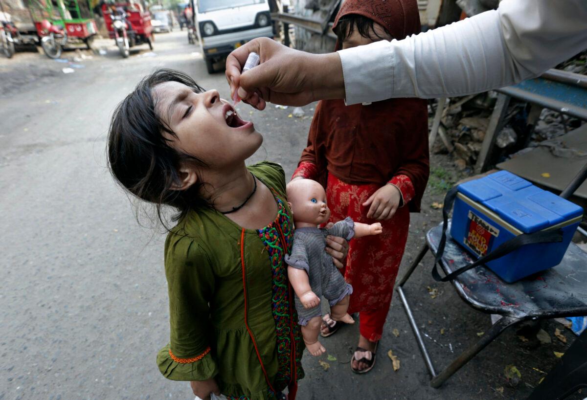 A health worker gives a polio vaccine to a girl on a street in Lahore, Pakistan, on June 27, 2022. Pakistan launched a new anti-polio drive with the goal to vaccinate a million children across Pakistan. (K.M. Chaudary/AP Photo)