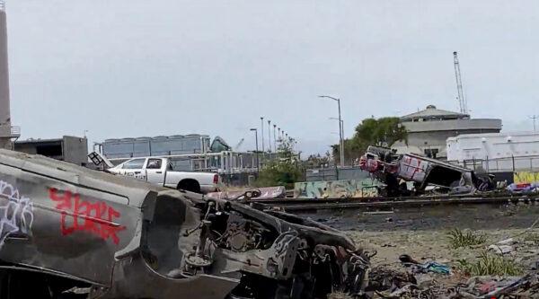 Burnt cars lie upside down in a homeless encampment in Oakland, Calif., on May 26, 2022. (Cynthia Cai/NTD Television)