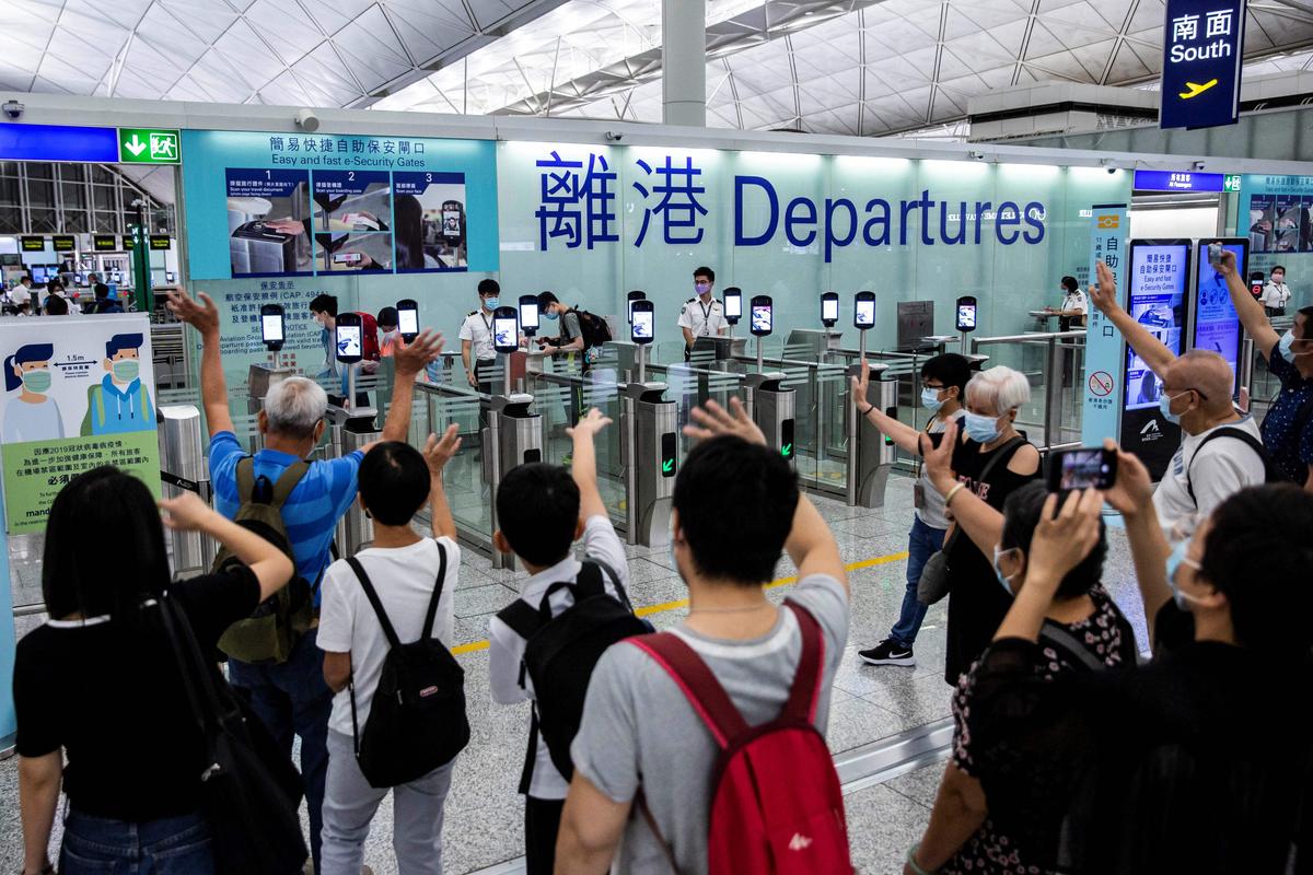 People (bottom) waving goodbye on July 22, 2021, as passengers make their way through the departure gates of Hong Kong's International Airport. Twice a day Hong Kong's virtually deserted airport fills with the sound of tearful goodbyes as residents, fearful for their future under China's increasingly authoritarian rule, start a new life abroad, mostly in Britain. (Isaac Lawrence/AFP via Getty Images)
