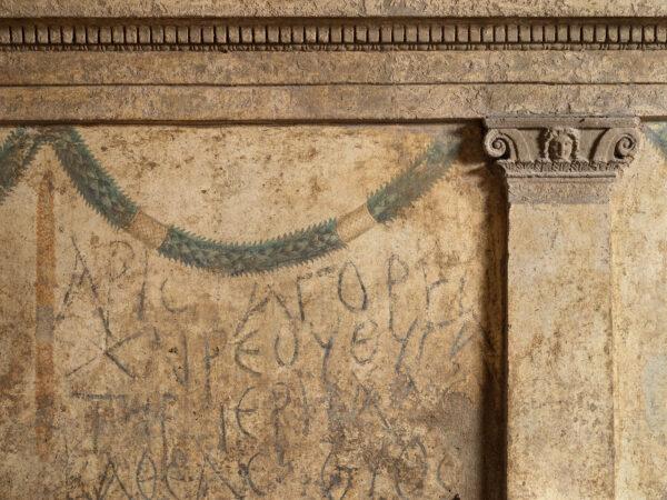 One of the more ornate burial chambers in the Ipogeo dei Cristallini features frescoed festoons strung between columns. Listed on this wall are the names of the Greeks and Romans who are buried in this tomb. (Luciano and Marco Pedicini)
