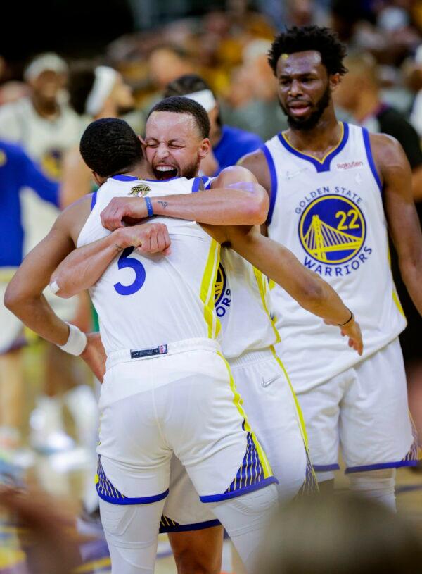 Golden State Warriors' Stephen Curry (30) hugs Jordan Poole (3) after Poole hit a long three point shot at the end of the third quarter of Game 2 of basketball's NBA Finals against the Boston Celtics in San Francisco, on June 5, 2022. (Carlos Avila Gonzalez/San Francisco Chronicle via AP)