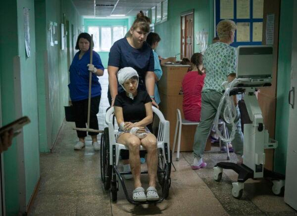 A hospital nurse pushes a wheelchair carrying a woman wounded by the Russian rocket attack at a shopping center in a city hospital in Kremenchuk in Poltava region, Ukraine, on June 28, 2022. (Efrem Lukatsky/AP Photo)