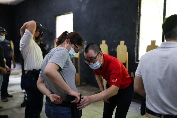 A trainer checks to see if a trainee's airsoft handgun is placed correctly in the holster during a basic training class at the shooting range of combat skill training company Polar Light, in New Taipei City, Taiwan, on May 29, 2022. Since the start of the Ukraine war, bookings have nearly quadrupled for lessons in how to shoot airsoft guns, low-power devices designed to shoot non-metallic projectiles.  Many of today's airsoft guns offer a realistic simulation of actual firearms. "More and more people are coming to take part," said Max Chiang, chief executive of Polar Light. (Reuters/Ann Wang)