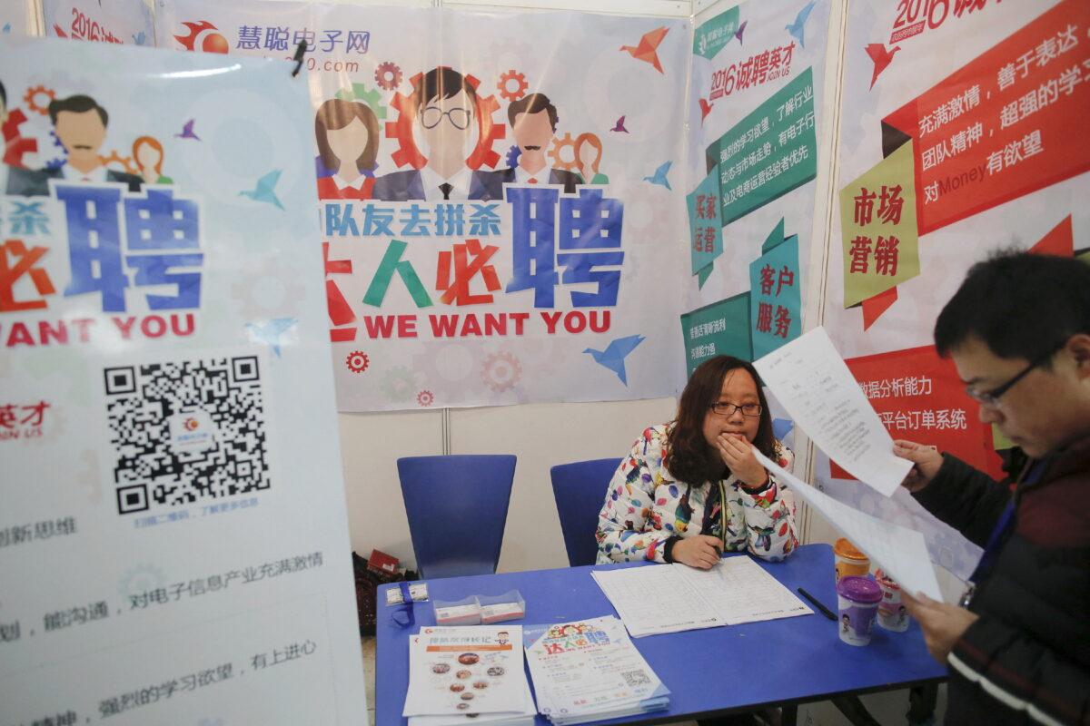 A man reads documents at a recruiters' booth at a job fair in Beijing on Feb. 26, 2016. (Damir Sagolj/Reuters)