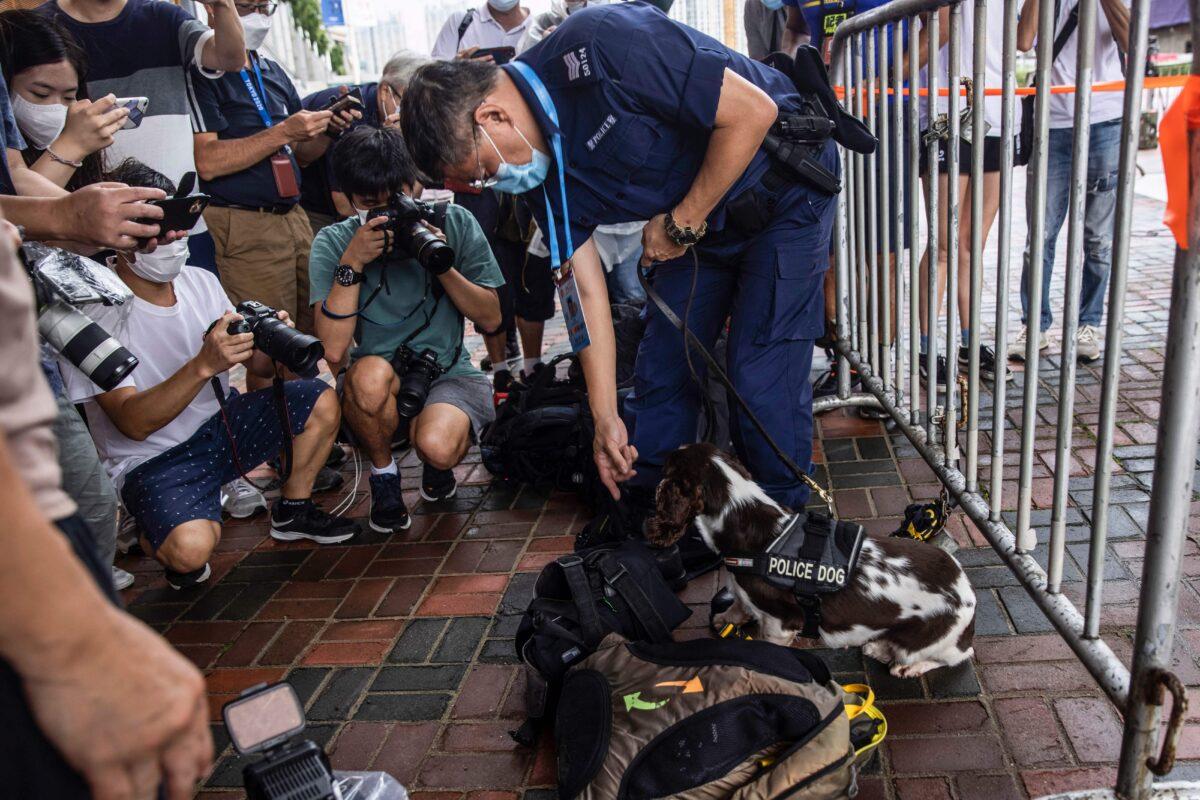 A police officer and sniffer dog (C) search the bags of media personnel near West Kowloon Station, as Chinese leader Xi Jinping arrives in Hong Kong to attend celebrations marking the 25th anniversary of the city's handover from Britain to China, in Hong Kong on June 30, 2022. (Isaac Lawrence/AFP via Getty Images)