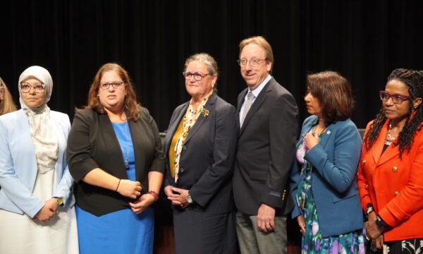 Michelle Reid (3rd L), superintendent of Fairfax County Public Schools, with her husband, Terry, and school board members (L–R) Abrar Omeish, Stella Pekarsky, Rachna Sizemore Heizer, and Karen Keys-Gamarra in Falls Church, Va., on June 30, 2022. (Terri Wu/The Epoch Times)
