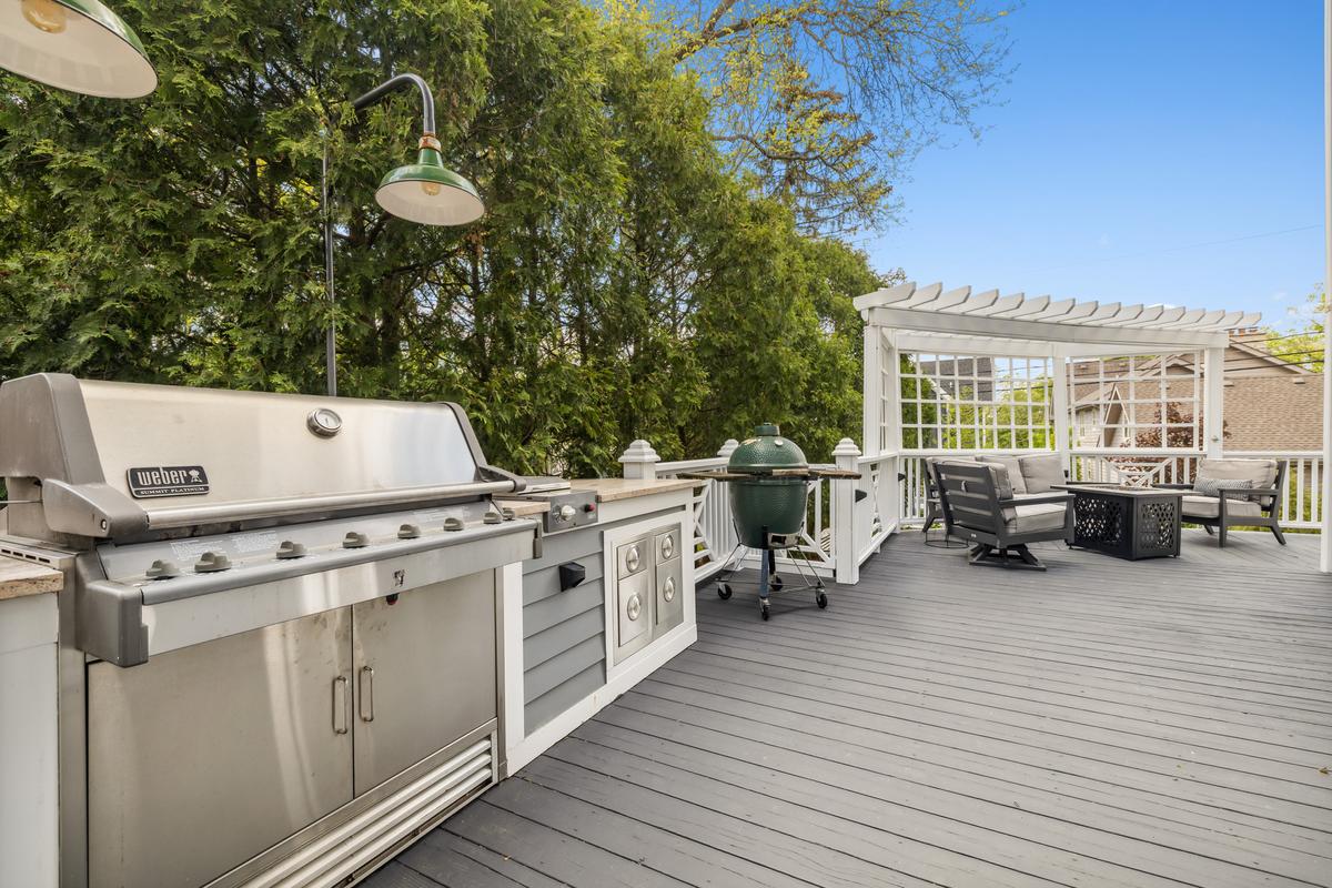 The wrap-around deck of the home features a pagoda, outdoor BBQ features, and cushy seating for relaxing outdoors. (Courtesy of Baird & Warner)