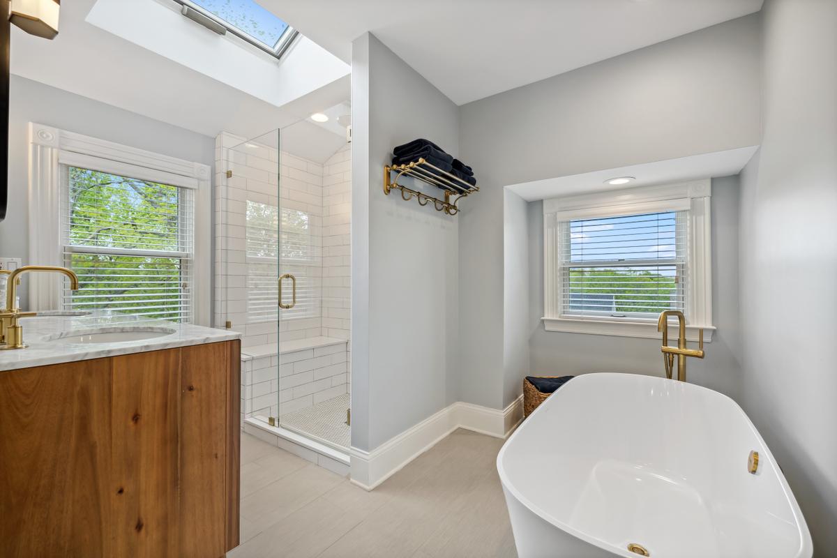 The top-floor master suite features a delightful bath area with a walk-in shower, soaking tub, and skylights to bring in ambient light. (Courtesy of Baird & Warner)