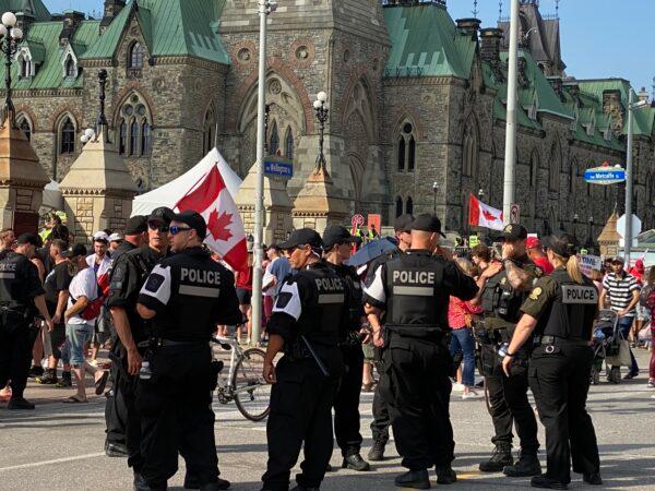 Police keep watch in downtown Ottawa as a huge crowd marches in protest of the federal government's COVID-19 vaccine mandate, on July 1, 2022. (Limin Zhou/The Epoch Times)