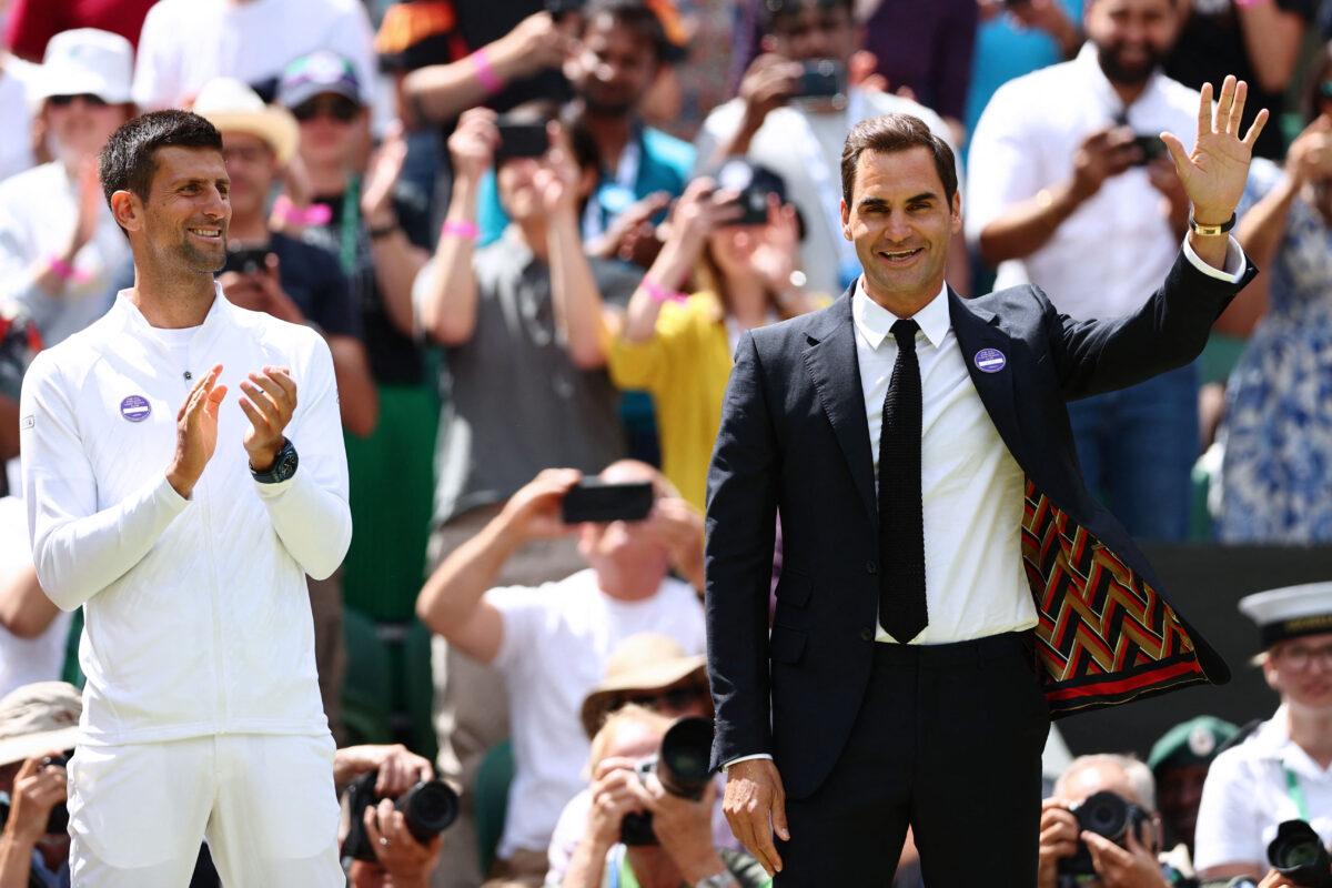 Swiss tennis player Roger Federer (R) waves next to Serbia's Novak Djokovic as they take part in the Centre Court Centenary Ceremony, on the seventh day of the 2022 Wimbledon Championships at The All England Tennis Club in Wimbledon, southwest London, on July 3, 2022. (Adrian Dennis/AFP via Getty Images)