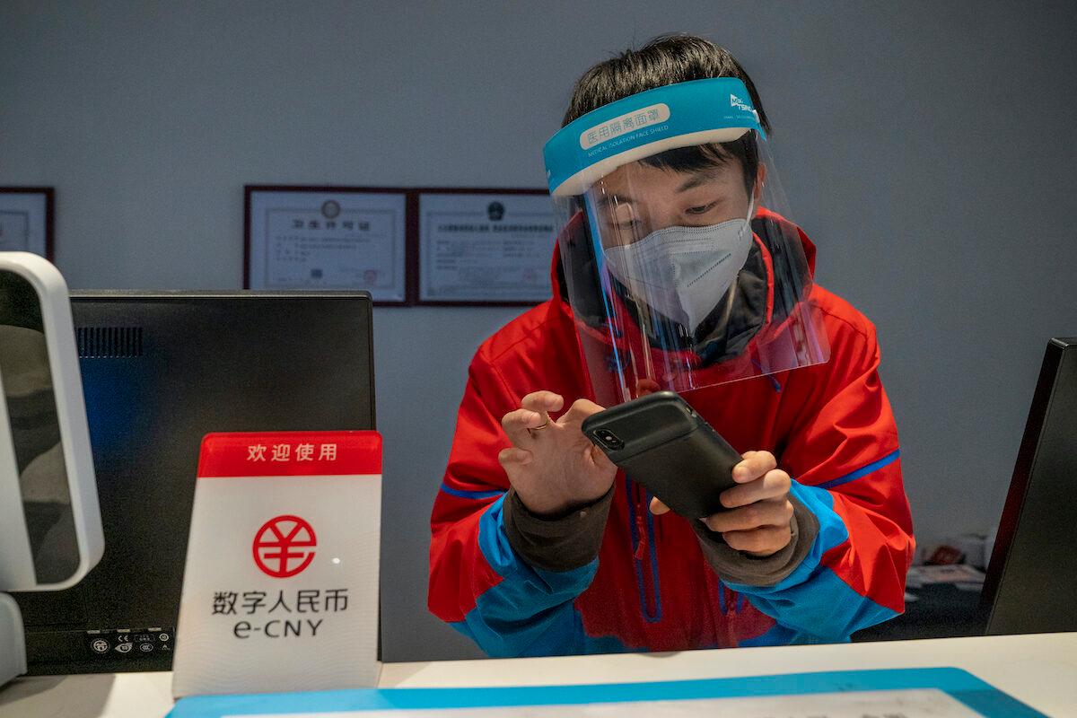 A worker at the front desk of Prince Ski Town Hotel checks the phone behind a sign saying "digital renminbi (e-CNY) is accepted" in Zhangjiakou, China, on Dec. 4, 2021. (Andrea Verdelli/Getty Images)