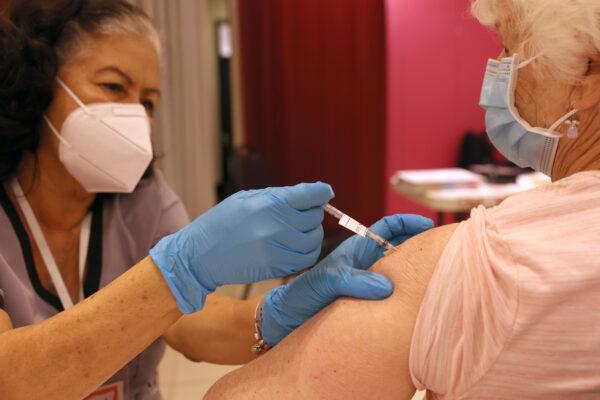 Registered Nurse Orlyn Grace (L) administers a COVID-19 booster vaccination to Jeanie Merriman (R) at a COVID-19 vaccination clinic on April 06, 2022, in San Rafael, California. (Justin Sullivan/Getty Images)