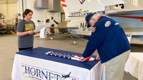 Keila Hurtado reads a script as Richard Keefer folds a U.S. flag at the USS Hornet Museum in Alameda, Calif., on June 28, 2022. (Ilene Eng/NTD Television)