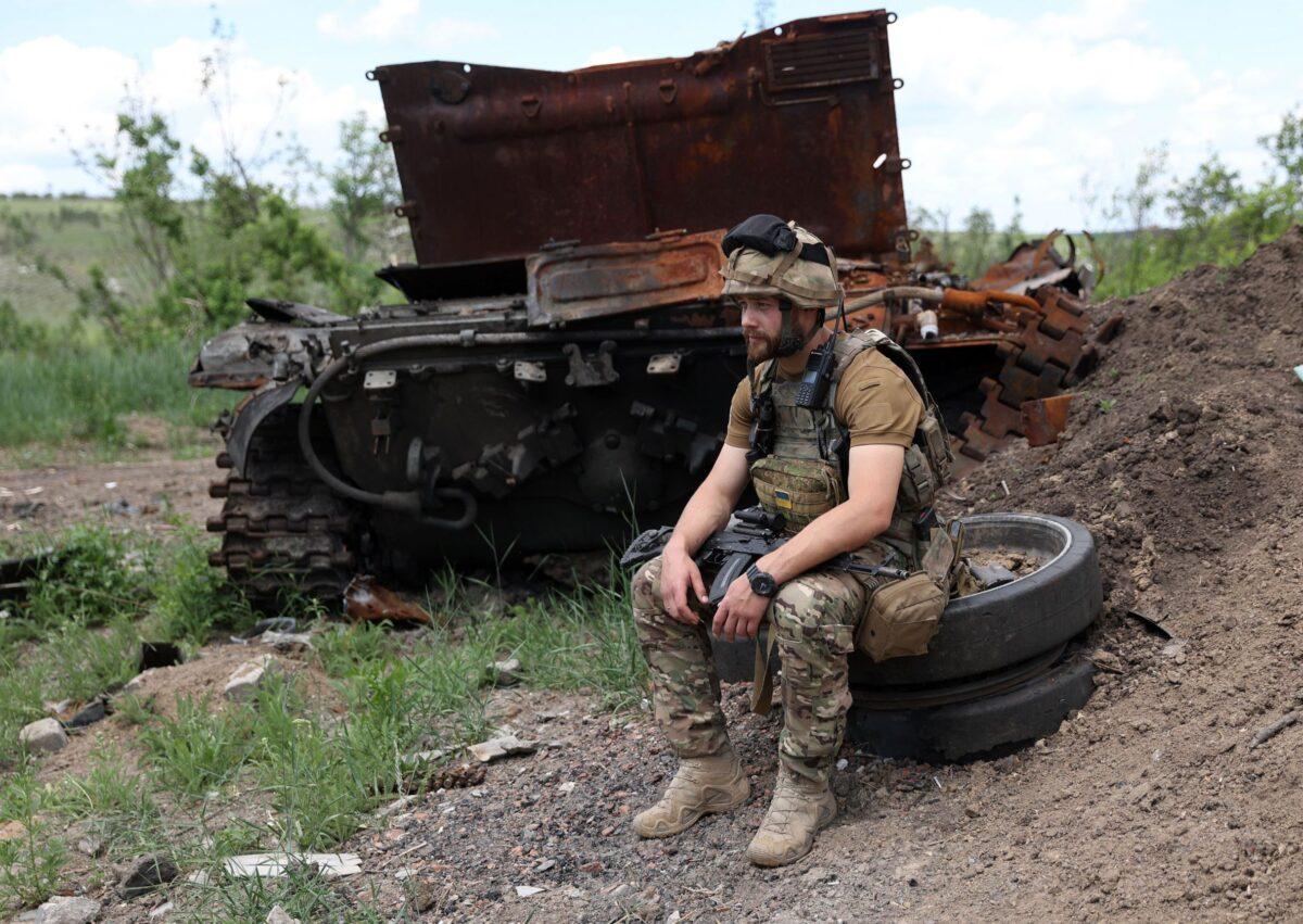 A Ukrainian serviceman sits next to a destroyed tank at an abandoned Russian position near the village of Bilogorivka not far from Lysychansk, Lugansk region, on June 17, 2022. (Anatolii Stepanov/AFP via Getty Images)