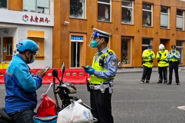 A police officer checks a delivery worker on a street in the Xuhui district of Shanghai on May 29, 2022. (Hector Retamal/AFP via Getty Images)