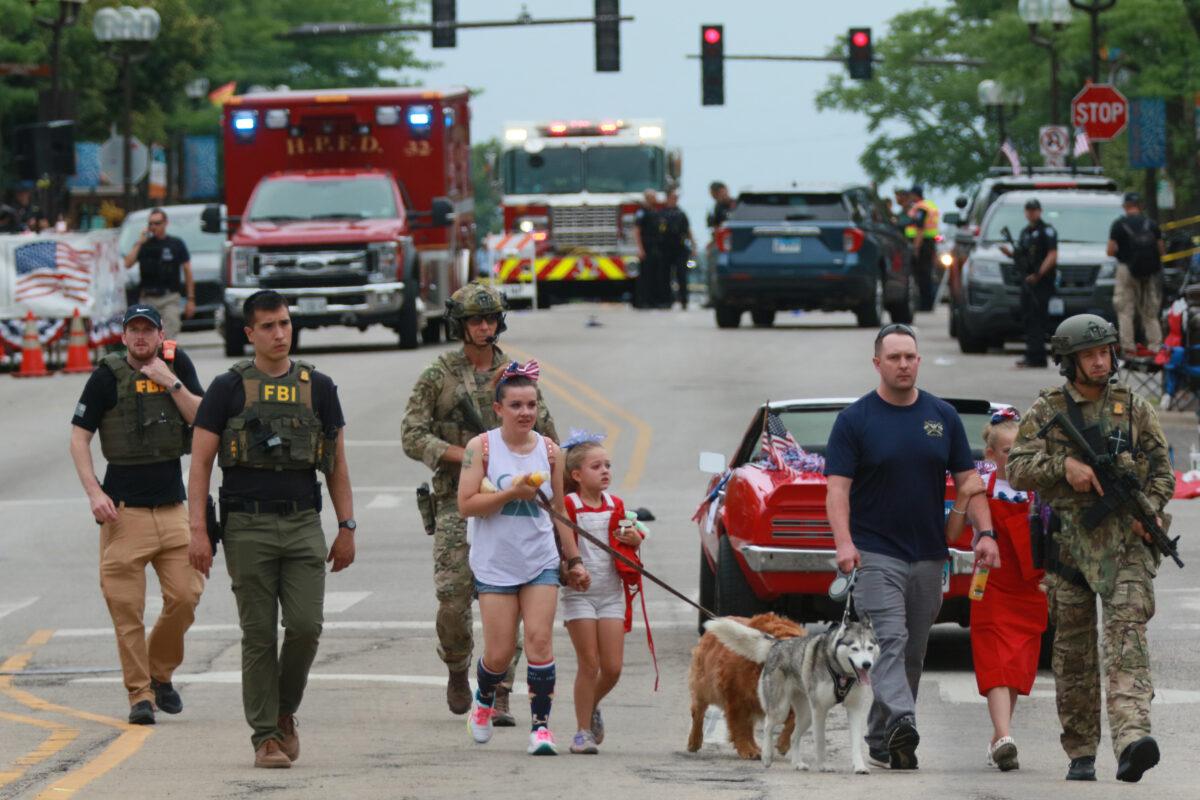 Law enforcement escorts a family away from the scene of a shooting at a Fourth of July parade in Highland Park, Illinois, on July 4, 2022. (Mark Borenstein/Getty Images)