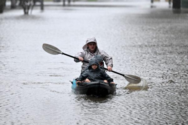 People kayak along a flooded street from the overflowing Hawkesbury river due to torrential rain in the Windsor suburb of Sydney, Australia, on July 4, 2022. (Saeed Khan/AFP via Getty Images)