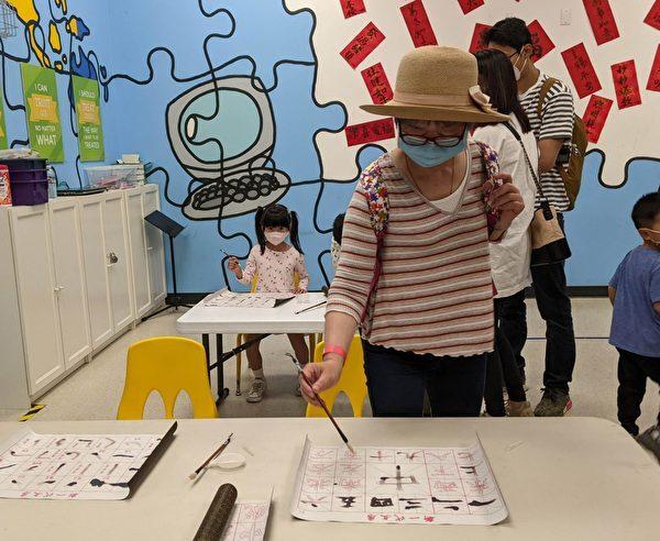 Parents and children experience the calligraphy at the Hong Kong Festival. (Emma Hsu/The Epoch Times)