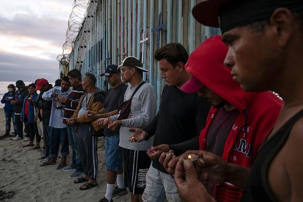 Migrants take part in a vigil for those who died while migrating to the United States, at the US-Mexico border in playas de Tijuana, Baja California state, Mexico, on July 4, 2022. (Guillermo Arias/AFP via Getty Images)