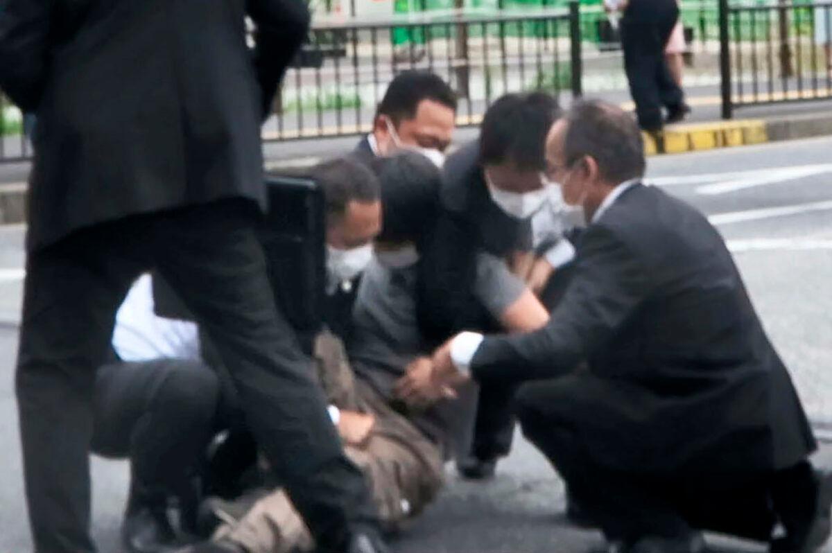 A man (C) is detained near the site of gunshots in Nara, western Japan, on July 8, 2022. (Kyodo News via AP)