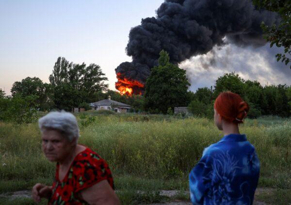 Local residents look on as smoke rises after strikes during the Ukraine-Russia conflict in Donetsk, Ukraine, on July 7, 2022. (Alexander Ermochenko/Reuters)