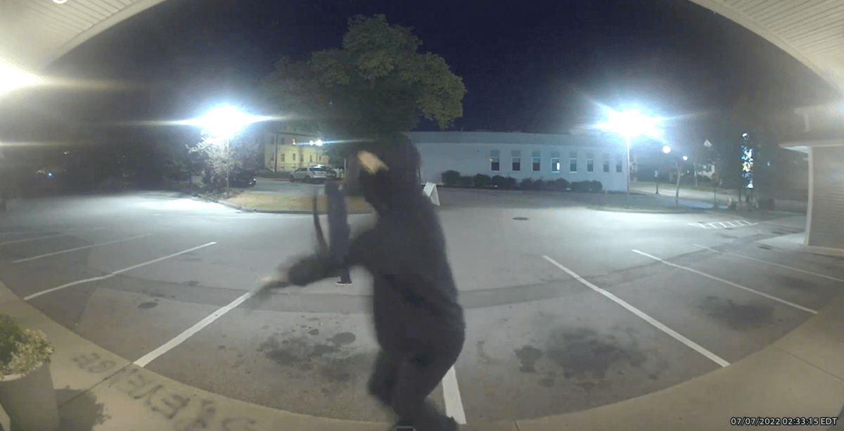 A masked assailant winds up to swing a hammer at a pregnancy clinic in Worcester, Massachusetts, on July 7, 2022. (Still from surveillance video/The Problem Pregnancy)