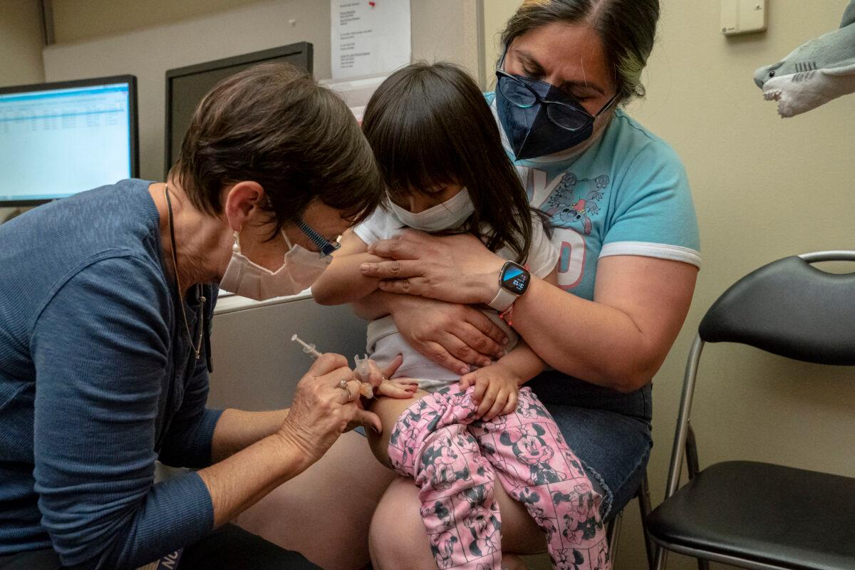  A 2-year-old receives her first dose of the Pfizer COVID-19 vaccination from a nurse while being held by her mother, at UW Medical Center-Roosevelt in Seattle, Wash., on June 21, 2022. (David Ryder/Getty Images)