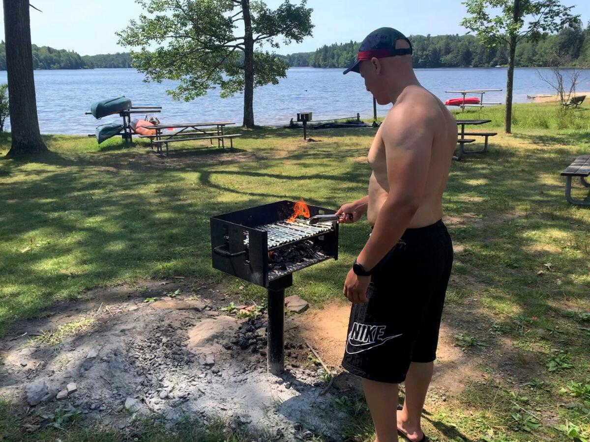 Mhamed Moussa Boudjelthia of New York works a grill at Promised Land State Park in Pennsylvania's Pocono Mountains on July 24, 2022. (Jeff McMillan/AP Photo)