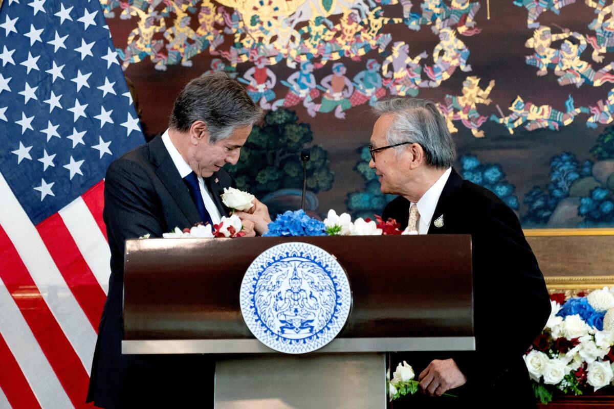 Thailand's Foreign Minister Don Pramudwinai (R) places a flower on the jacket of U.S. Secretary of State Antony Blinken following remarks to the press after a Memorandum of Understanding signing ceremony at the Thai Ministry of Foreign Affairs in Bangkok, Thailand, on July 10, 2022. (Stefani Reynolds/Reuters)