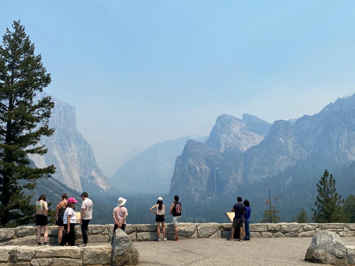 Visitors check out the view from the east end of the Wawona Tunnel into Yosemite Valley, showing three major landmarks, from the left, El Capitan, Half Dome and Bridalveil Fall, obscured by thick smoke in the area from the wildfire burning to the south in the Mariposa Grove of Giant Sequoias, at Yosemite National Park, Calif., on July 9, 2022. (Courtesy of U.S. National Park Service/Handout via Reuters)