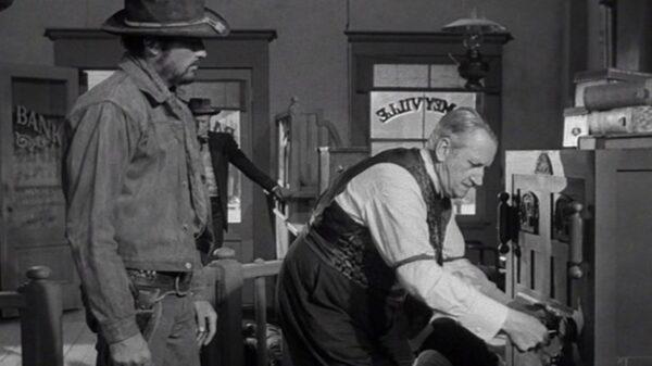 Stretch (Gregory Peck, L) demands a bank teller to hand over the bank's money, as Dude (Richard Widmark) looks on in the background, in “Yellow Sky.” (Twentieth Century Fox)