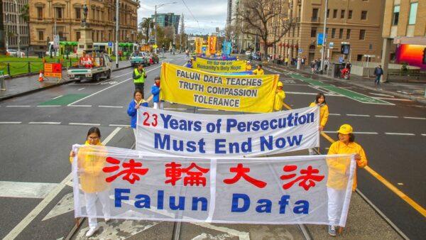 Falun Dafa practitioners holding banners as they walk along Spring St., Melbourne, Australia, during a commemoration event on July 9, 2022. (Chen Ming/Epoch Times)