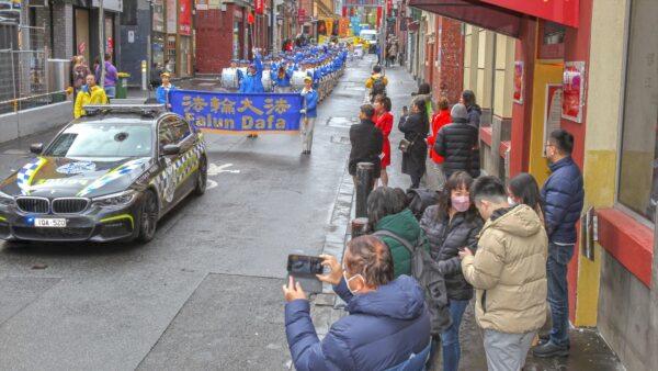 Members of the public take photos and observe the Falun Dafa march in Chinatown on July 9, 2022. (Chen Ming/Epoch Times)