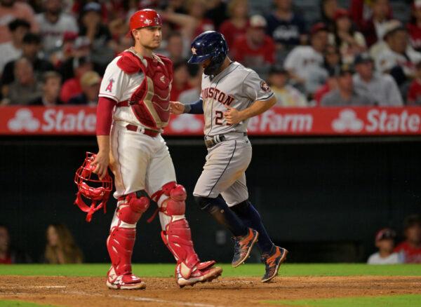 Jose Altuve #27 of the Houston Astros scores the go-ahead run past Max Stassi #33 of the Los Angeles Angels on a double by Kyle Tucker #30 in the eighth inning at Angel Stadium of Anaheim, in Anaheim, on July 12, 2022. (Jayne Kamin-Oncea/Getty Images)