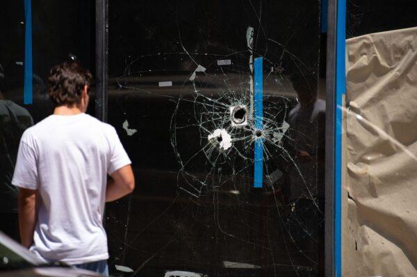 A pedestrian walks past bullet holes in the window of a store front on South Street in Philadelphia, Pennsylvania, on June 5, 2022. (Kriston Jae Bethel/AFP)