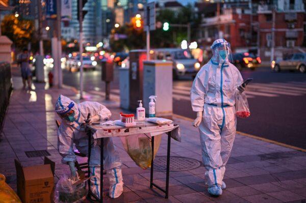 Health workers wait to test people for COVID-19 on a street next to a residential area in the Jing'an district of Shanghai on July 5, 2022. (Hector Retamal/AFP via Getty Images)