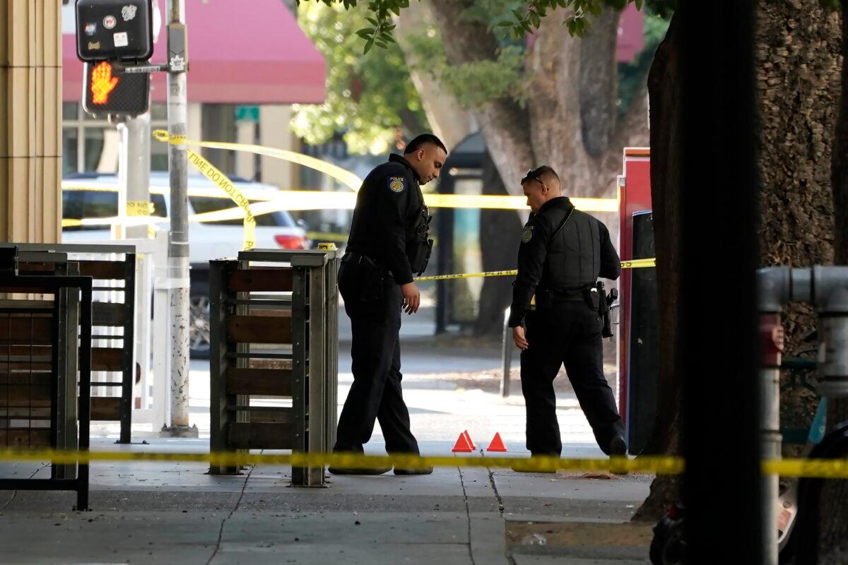 Sacramento police officers look over evidence markers near the scene of a fatal shooting outside of a downtown Sacramento, Calif., night club in the early morning hours on July 4, 2022. (Rich Pedroncelli/AP Photo)