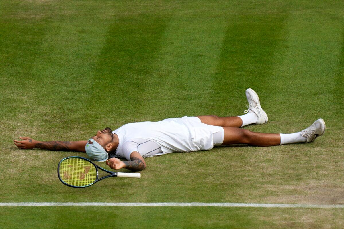 Australia's Nick Kyrgios lies on the ground after defeating Chile's Cristian Garin during a men's singles quarterfinal match on day ten of the Wimbledon tennis championships in London on July 6, 2022. (Alastair Grant/AP Photo)