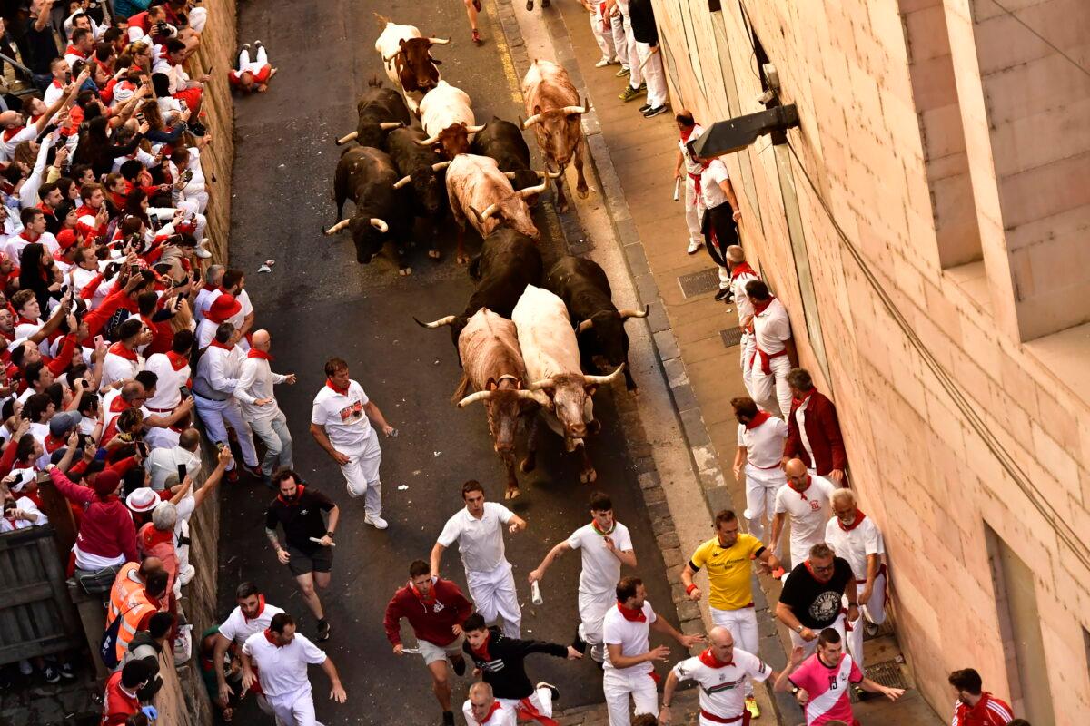 People run through the street with fighting bulls at the San Fermin Festival in Pamplona, northern Spain, on July 8, 2022. (Alvaro Barrientos/AP Photo)
