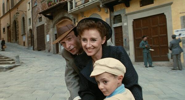 Before the happy family is taken to the camp. (L–R) Guido (Roberto Benigni), Dora (Nicoletta Braschi), and Giosuè (Giorgio Cantarini), in “Life is Beautiful.” (Melampo Cinematografica)