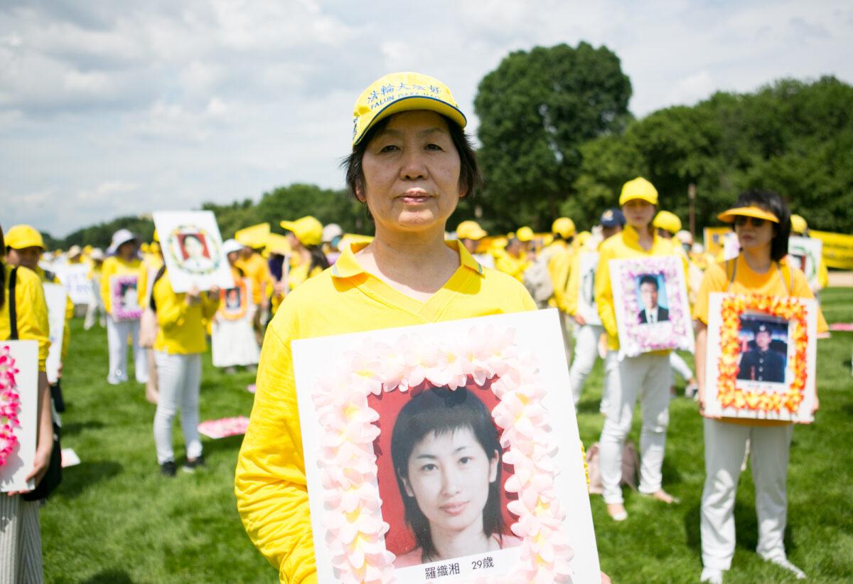 Wang Chunyan holds a wreath showing a Falun Gong practitioner who was killed in China for her belief, at a rally on the National Mall in Washington on July 21, 2022. (Lisa Fan/The Epoch Times)