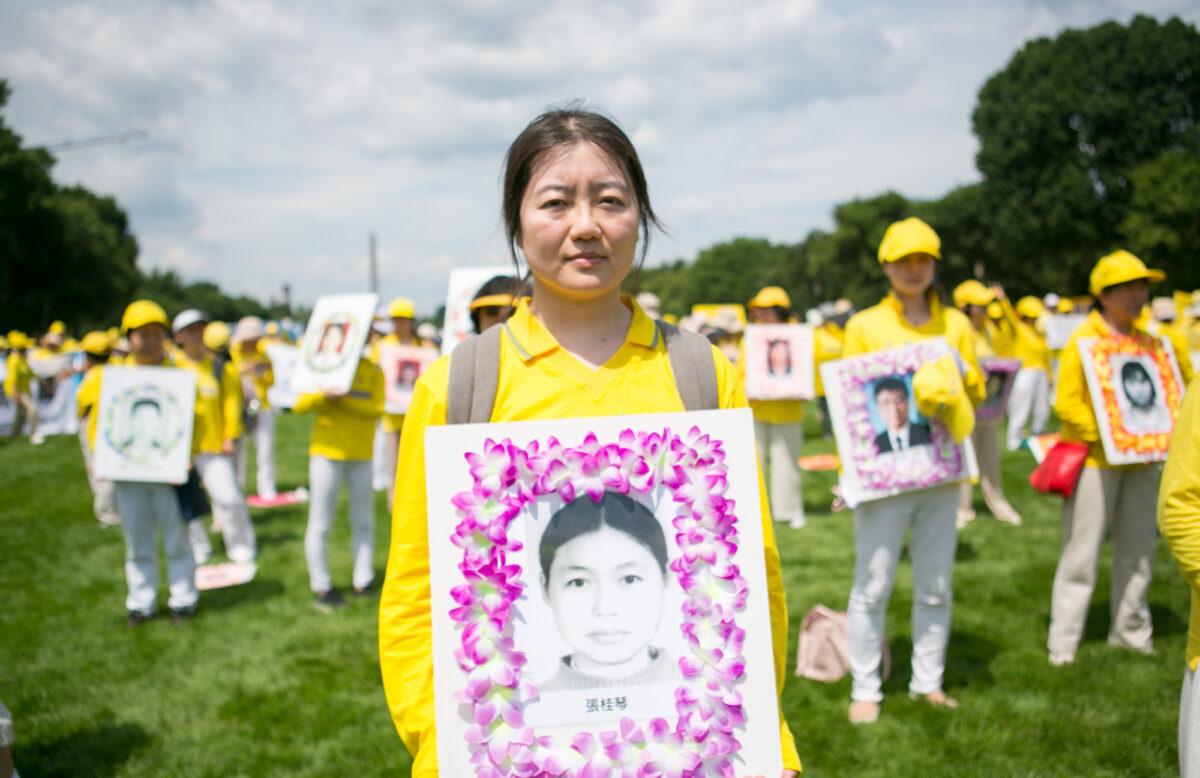 Yu Ping at a rally held on the National Mall in Washington on July 21, 2022, holding a picture of a Falun Gong practitioner killed in the persecution in China. (Lisa Fan/The Epoch Times)