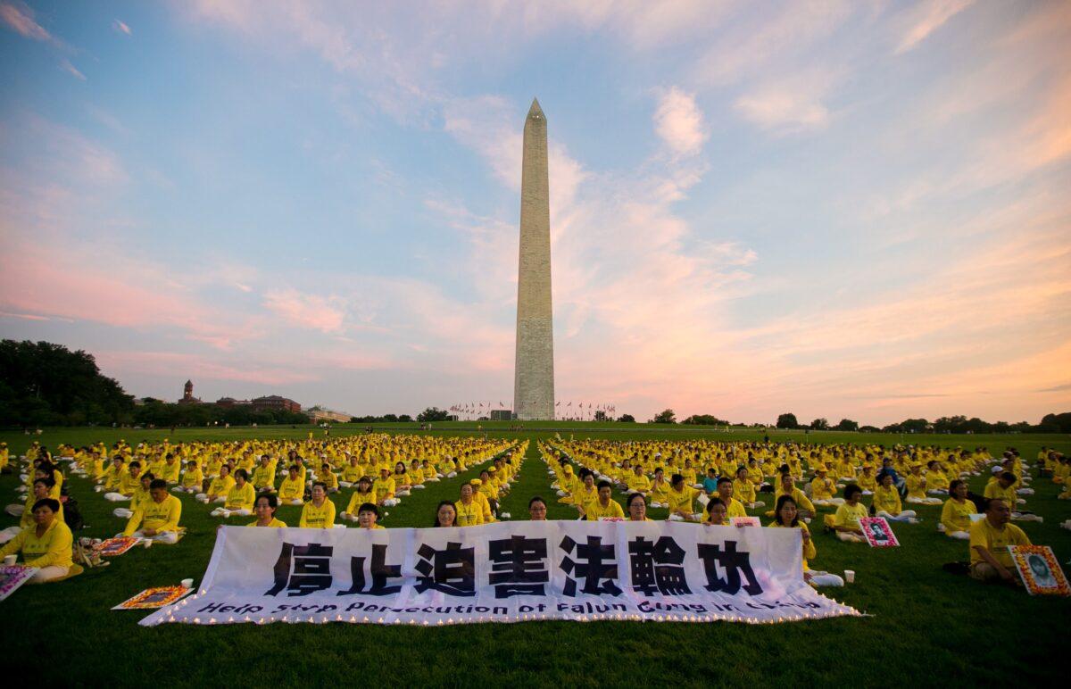 Falun Gong practitioners hold a banner calling for an end to the 23-year-long persecution in China, ahead of a candlelight vigil in front of the Washington Monument on July 21, 2022. (Lisa Fan/The Epoch Times)
