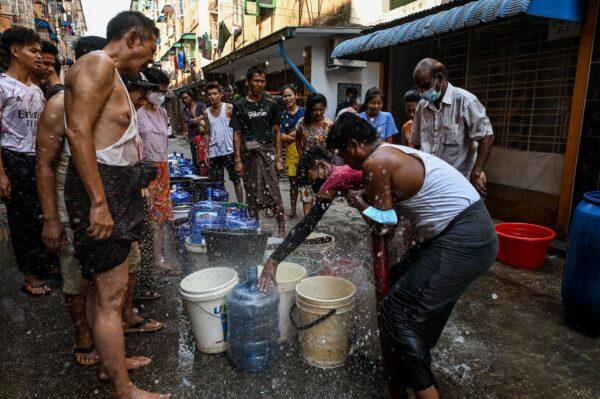 People react as water sprays while filling up containers in Yangon on March 14, 2022, as thousands of people faced water shortages due to power outages in the city. (STR/AFP via Getty Images)
