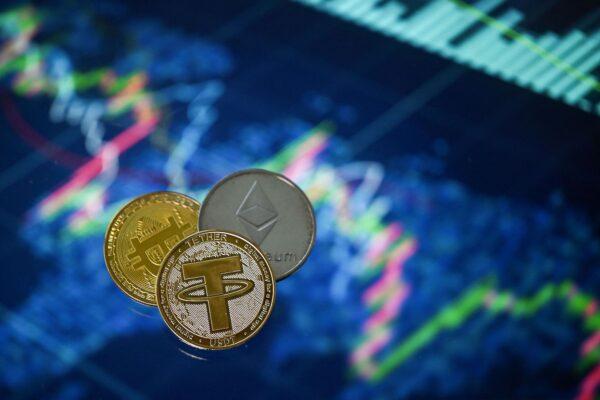 Gold-plated souvenir cryptocurrency Tether (USDT), Bitcoin, and Etherium coins arranged beside a screen displaying a trading chart in an illustration picture taken in London on May 8, 2022. (Justin Tallis/AFP via Getty Images)