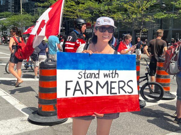 A woman holds a sign with the colours of the Dutch flag to show her solidarity with farmers protesting the Dutch government's climate change policies, in Ottawa on July 23, 2022. (Annie Wu/The Epoch Times)